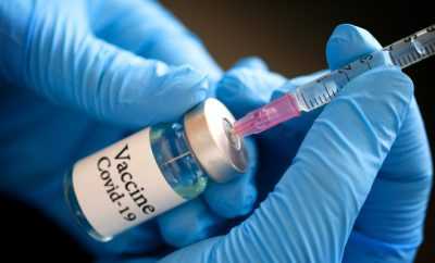 Doctor's hand holds a syringe and a blue vaccine covid19 bottle at the hospital. Health and medical concepts