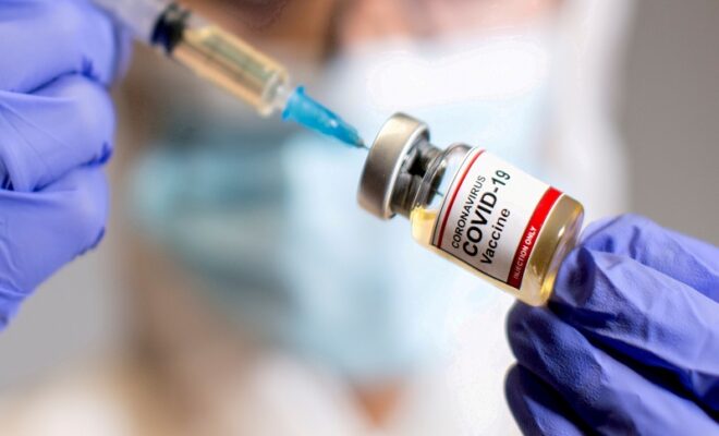 file photo: file photo: a woman holds a medical syringe and a small bottle labelled "coronavirus covid 19 vaccine