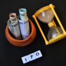 ipo written with blocks along with sand clock and pot with indian currency.