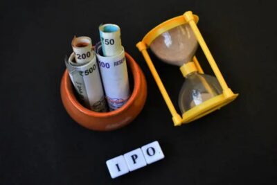 ipo written with blocks along with sand clock and pot with indian currency.