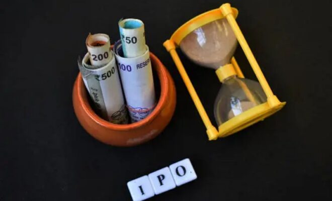 ipo written with blocks along with sand clock and pot with indian currency.