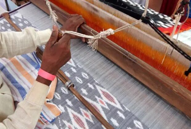 view of indian man weaving cloth on hand loom machine