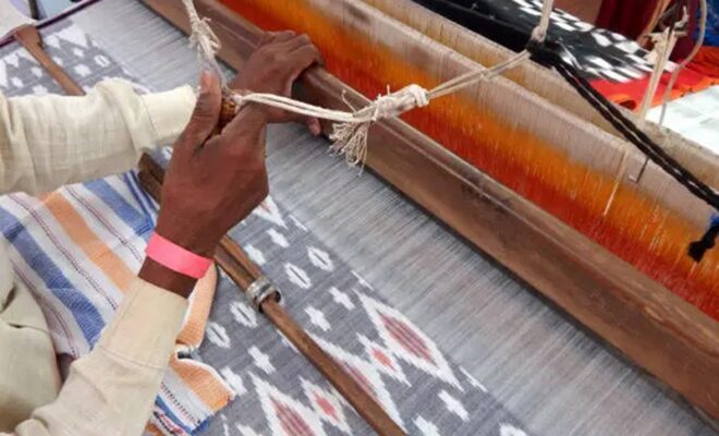 view of indian man weaving cloth on hand loom machine